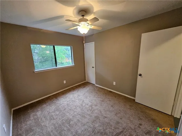 en empty room with a chandelier fan and hardwood floor