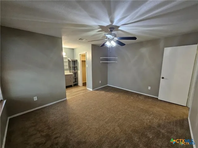 an empty room with a ceiling fan and a window