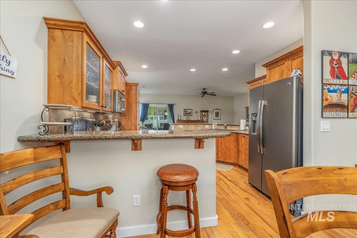 3038 North Christian Way Meridian, ID 83646 - Photo 11 of 48 Kitchen featuring a kitchen bar, a peninsula, wood finish cabinets, stainless steel appliances, and glass insert cabinets