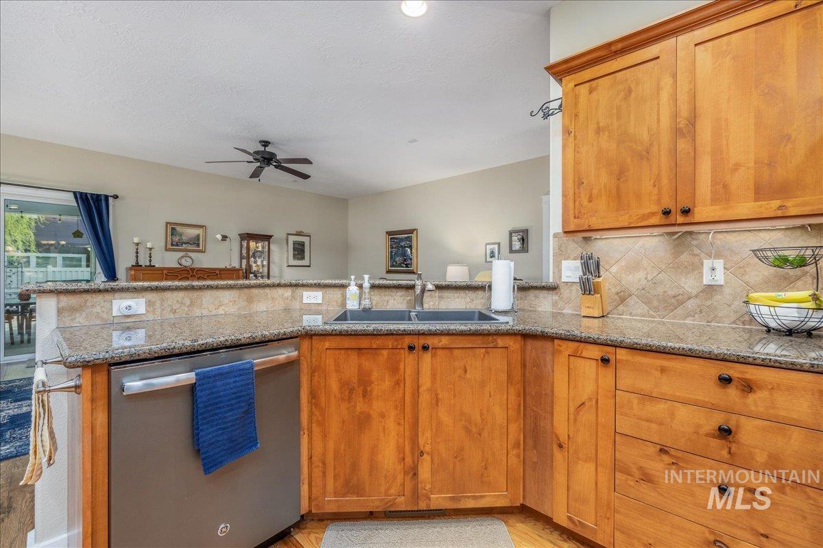 3038 North Christian Way Meridian, ID 83646 - Photo 12 of 48 Kitchen with dishwasher, light stone counters, a peninsula, wood finish cabinets, and ceiling fan