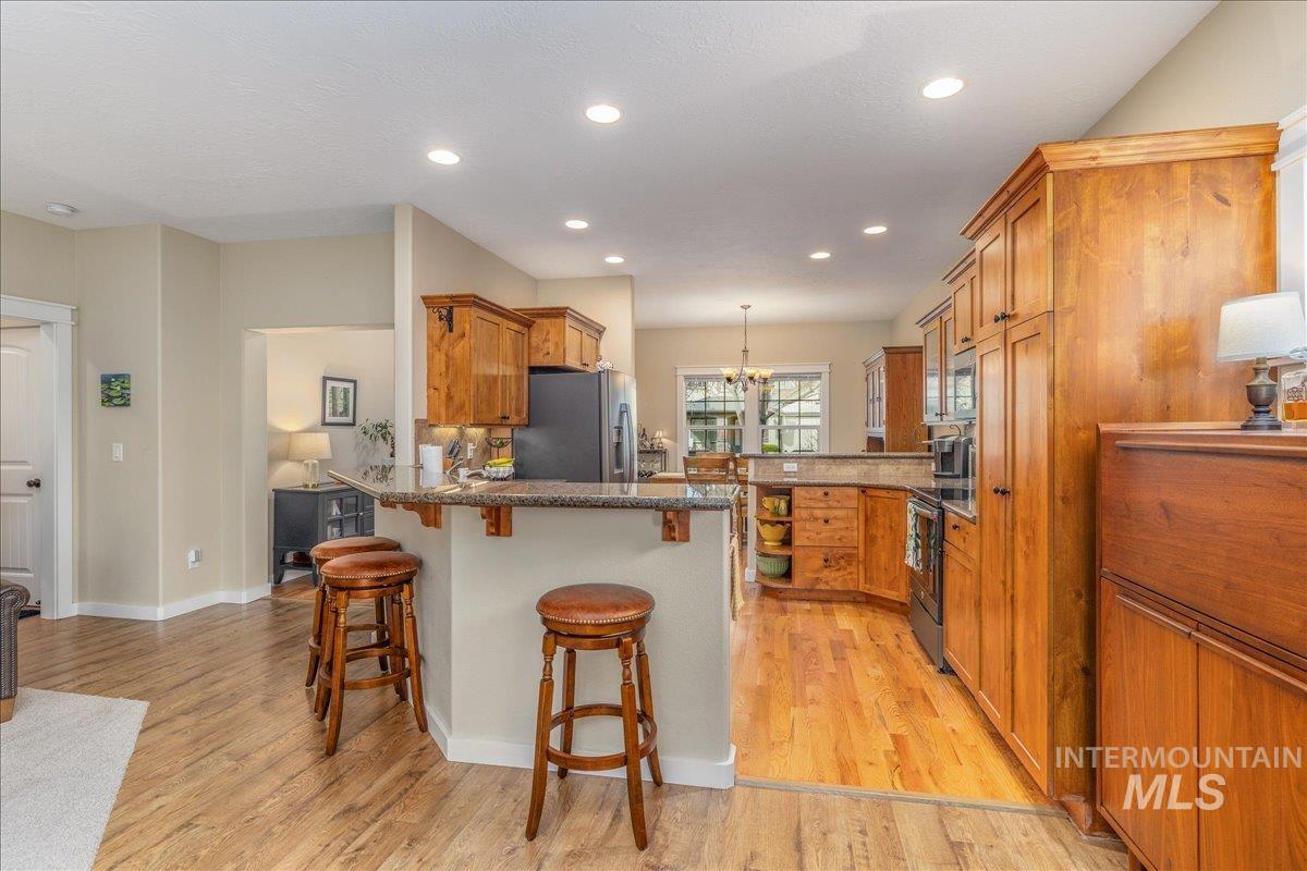 3038 North Christian Way Meridian, ID 83646 - Photo 13 of 48 Kitchen with wood finish cabinetry, a peninsula, a breakfast bar area, a chandelier, and dark stone countertops