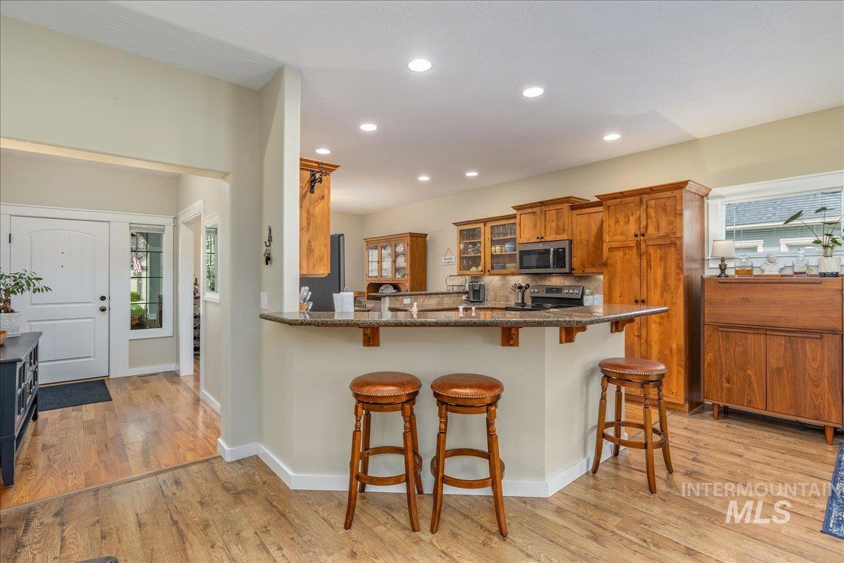 3038 North Christian Way Meridian, ID 83646 - Photo 14 of 48 Kitchen with wood finish cabinets, a breakfast bar area, a peninsula, light wood-type flooring, and recessed lighting