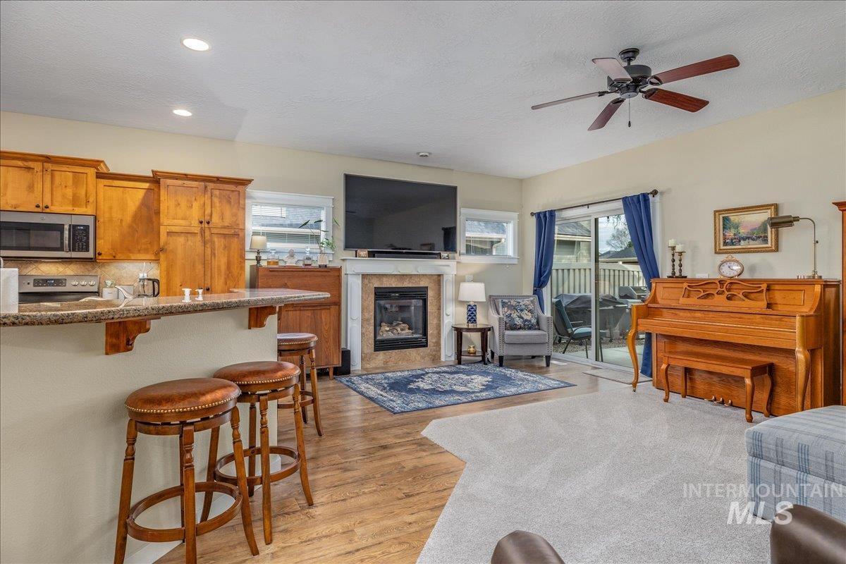 3038 North Christian Way Meridian, ID 83646 - Photo 16 of 48 Living area featuring a tile fireplace, ceiling fan, light wood-style flooring, plenty of natural light, and a textured ceiling