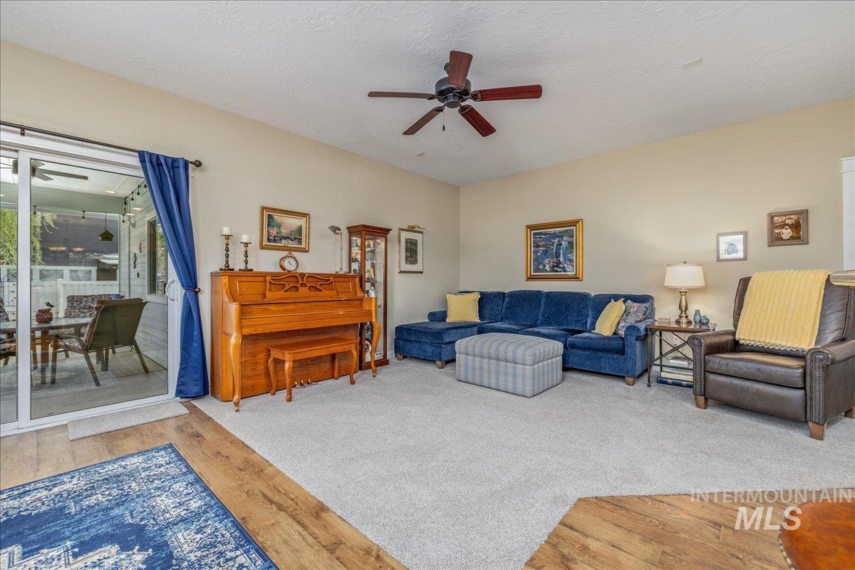 3038 North Christian Way Meridian, ID 83646 - Photo 17 of 48 Living room featuring ceiling fan, light carpet, light wood-style flooring, and a textured ceiling