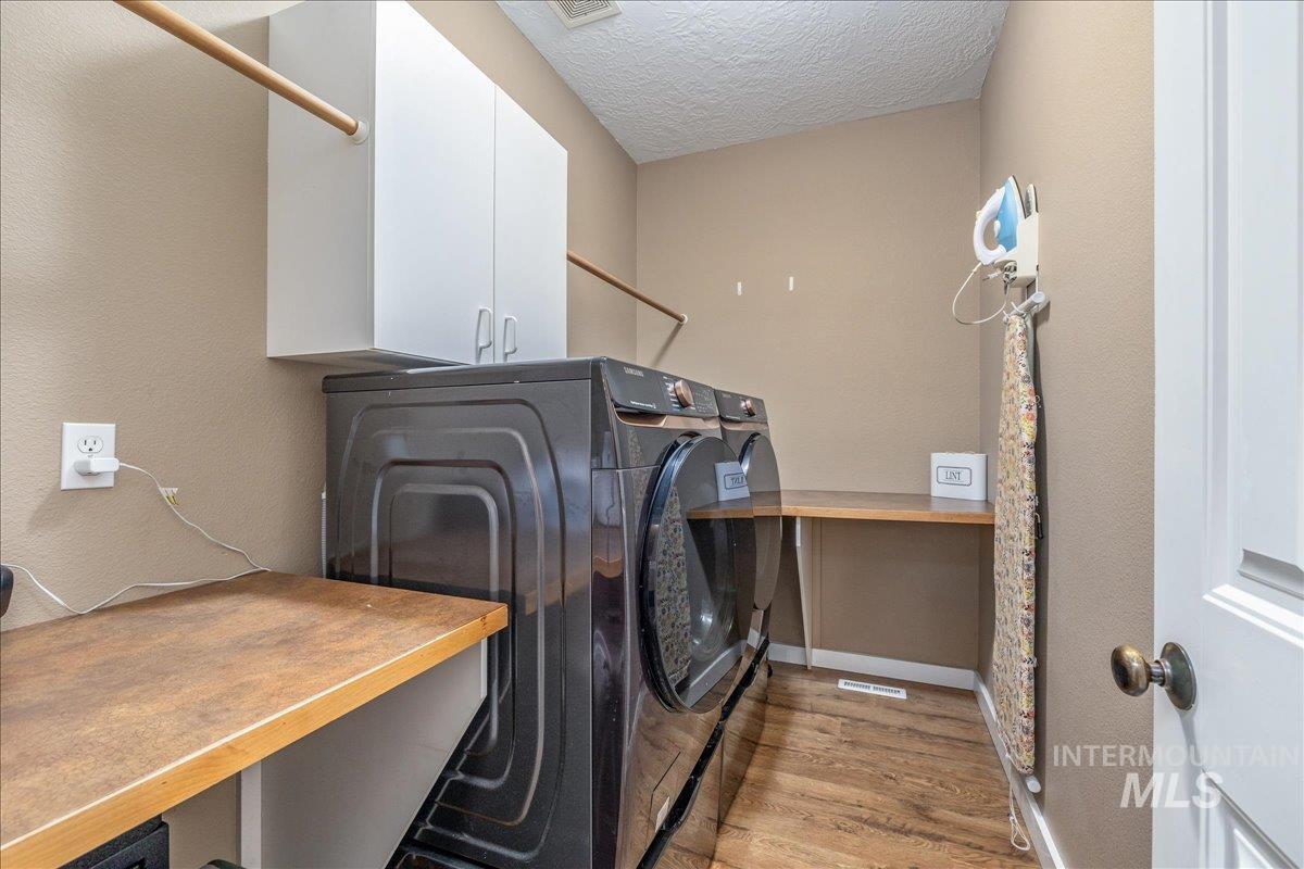 3038 North Christian Way Meridian, ID 83646 - Photo 19 of 48 Laundry area featuring light wood-style floors, cabinet space, a textured ceiling, a textured wall, and separate washer and dryer