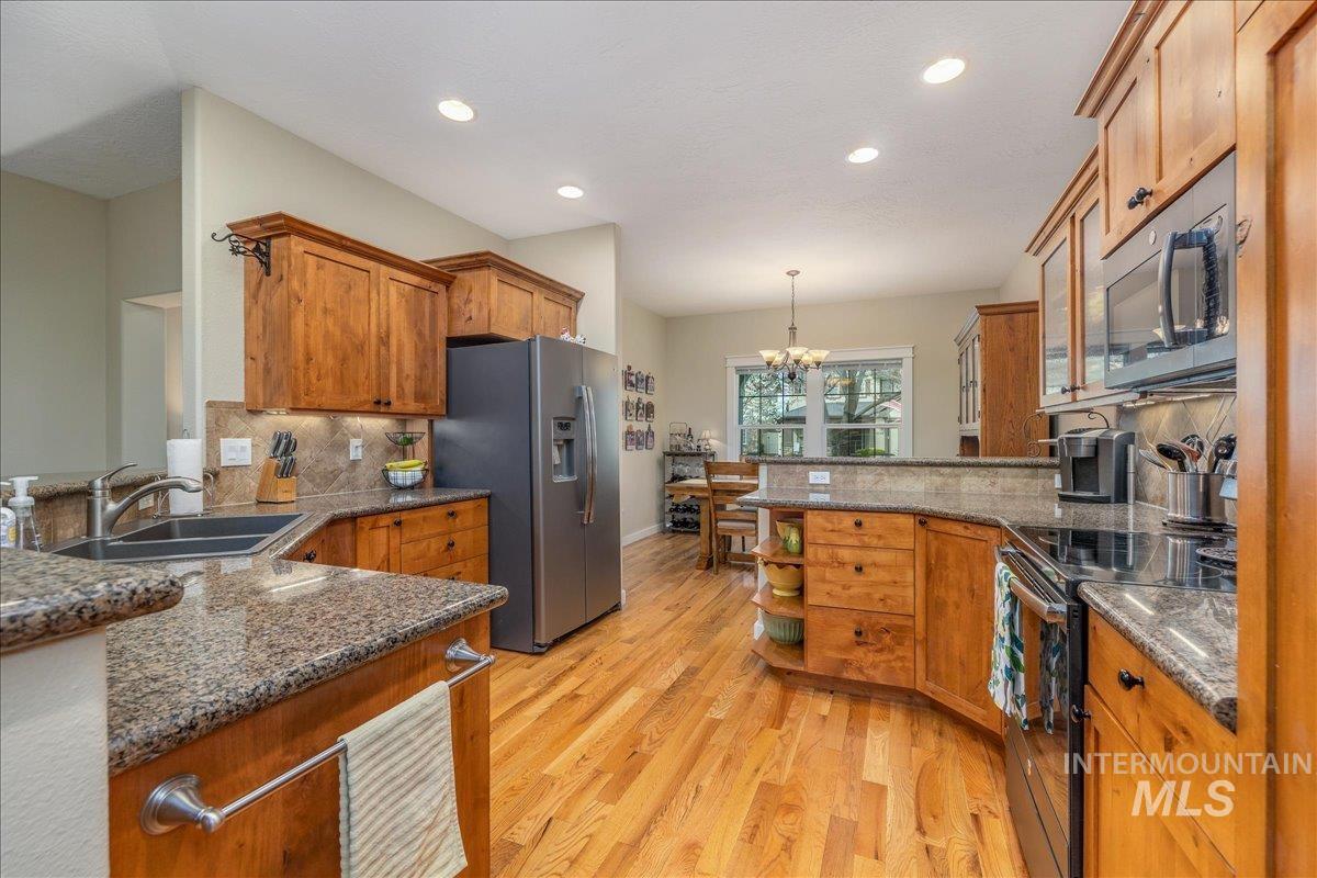 3038 North Christian Way Meridian, ID 83646 - Photo 9 of 48 Kitchen with a peninsula, wood finish cabinets, stainless steel fridge, and black range with electric cooktop