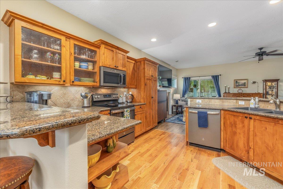 3038 North Christian Way Meridian, ID 83646 - Photo 10 of 48 Kitchen featuring glass fronted cabinets, wood finish cabinets, a breakfast bar, stainless steel appliances, and dark stone counters