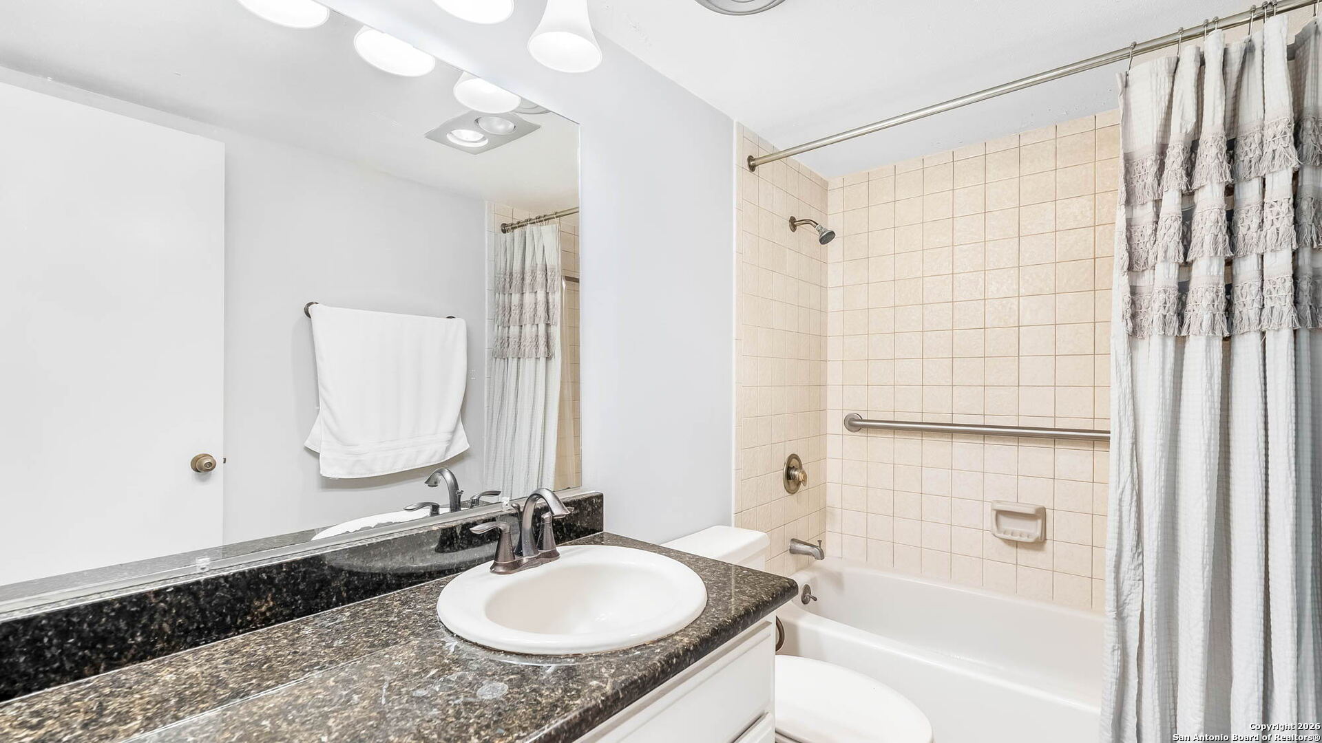 7701 Wurzbach Road, Unit 606 San Antonio, TX 78229 - Photo 4 of 10 a bathroom with a granite countertop sink a mirror and shower