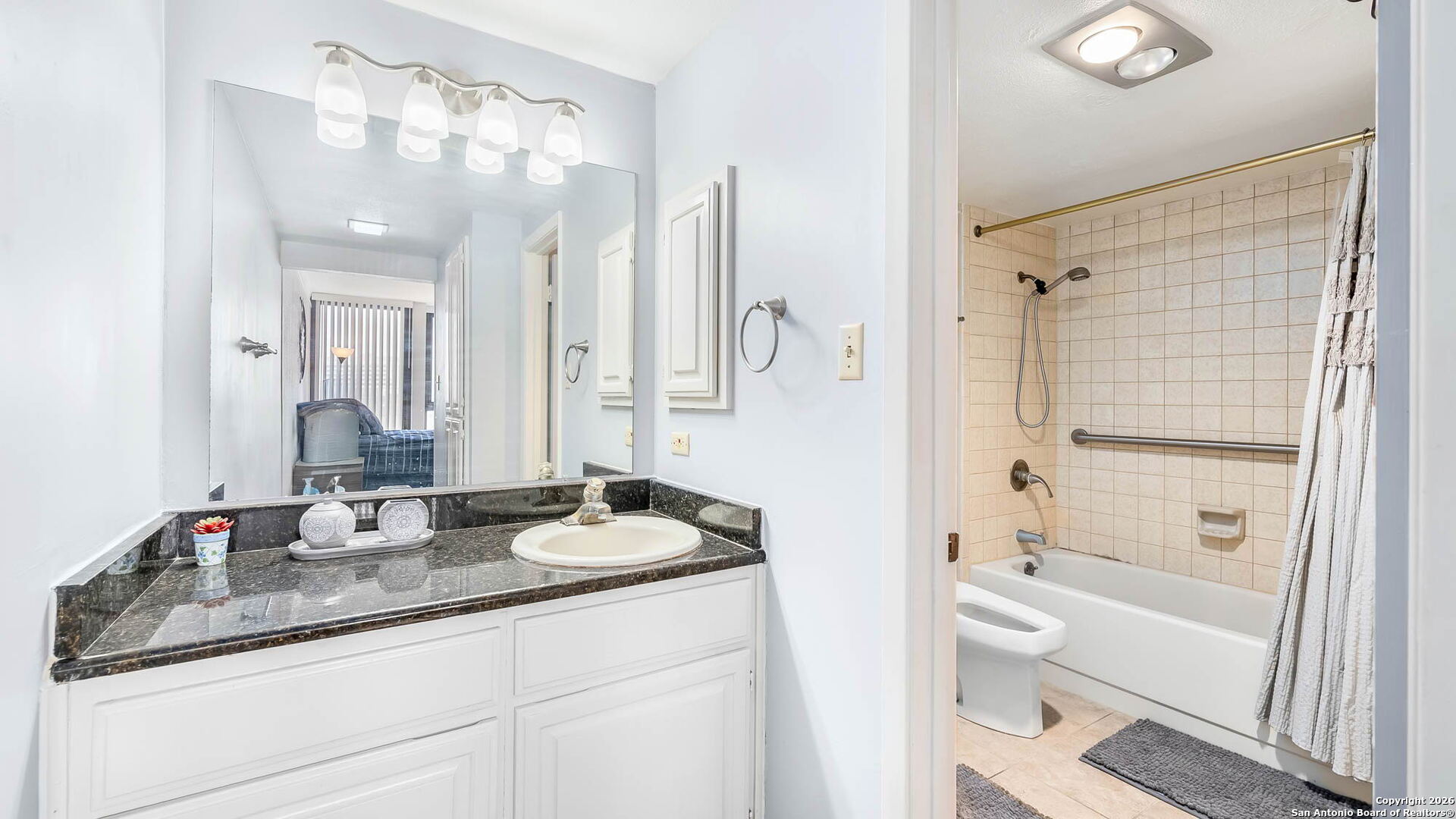 7701 Wurzbach Road, Unit 606 San Antonio, TX 78229 - Photo 8 of 10 a bathroom with a granite countertop sink mirror and a bathtub