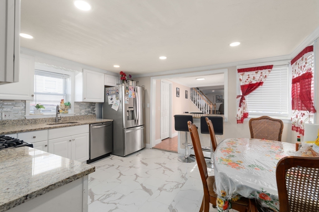 84 Howard Street Lawrence, MA 01841 - Photo 12 of 28 a kitchen with stainless steel appliances kitchen island granite countertop a refrigerator a stove a sink a dining table and chairs
