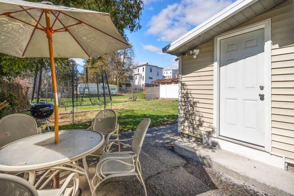 84 Howard Street Lawrence, MA 01841 - Photo 26 of 28 a patio with a table and chairs under an umbrella