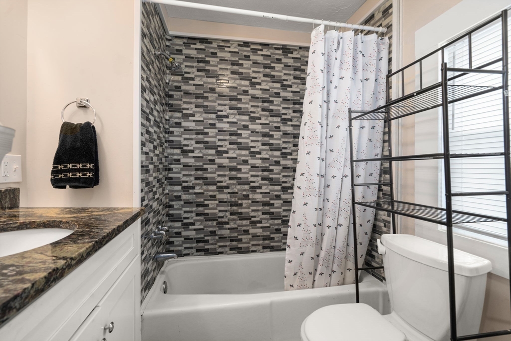 84 Howard Street Lawrence, MA 01841 - Photo 5 of 28 a bathroom with a granite countertop bathtub sink vanity mirror and toilet