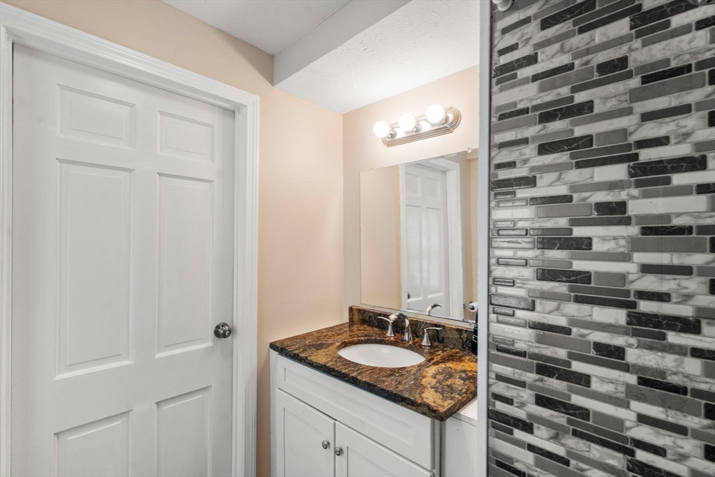 84 Howard Street Lawrence, MA 01841 - Photo 6 of 28 a bathroom with a granite countertop sink and a mirror