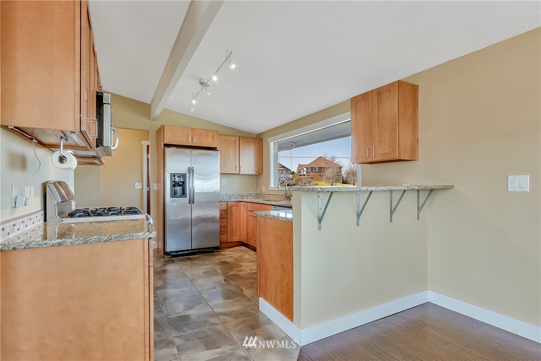 5874 Laurel Ridge Way Bellingham, WA 98226 - Photo 12 of 40 a kitchen with stainless steel appliances granite countertop a refrigerator a sink dishwasher a stove and white countertops with wooden floor