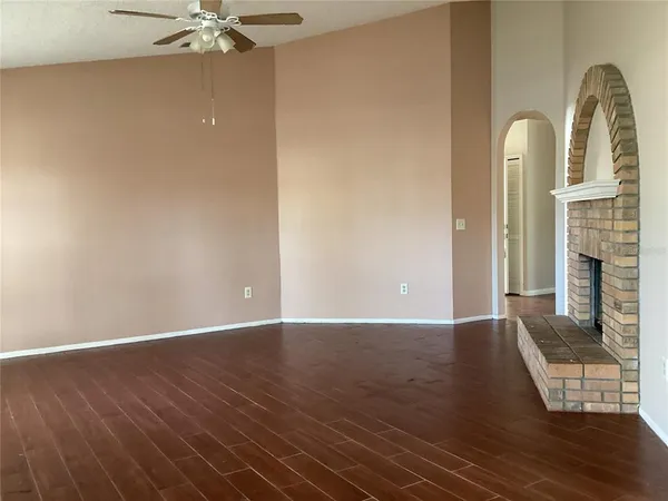an empty room with wooden floor a fireplace and a window