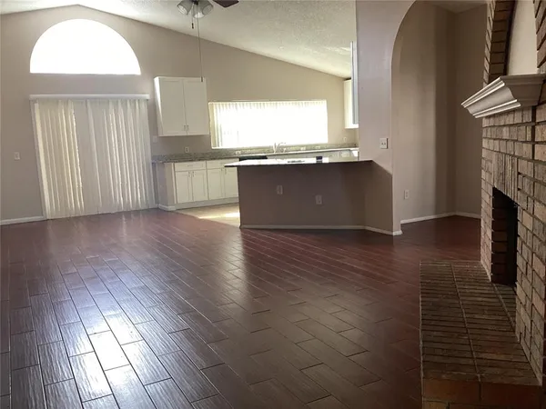 an empty room with wooden floor fireplace and hallway