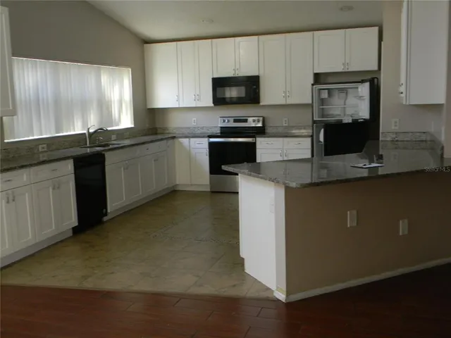 a kitchen with stainless steel appliances granite countertop a stove a sink a microwave a refrigerator and cabinets