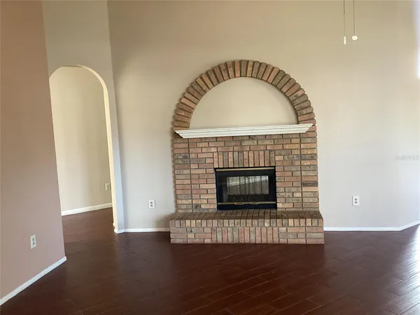 an empty room with wooden floor fireplace and windows