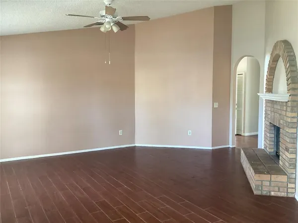a view of empty room with a fireplace and wooden floor