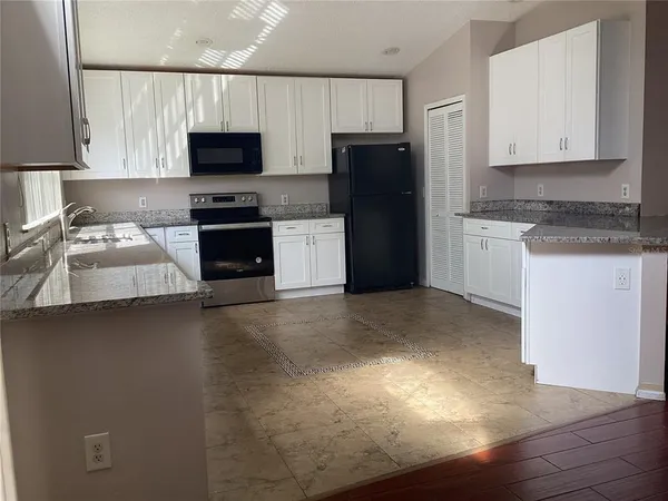 a view of an empty room with wooden floor and a fireplace