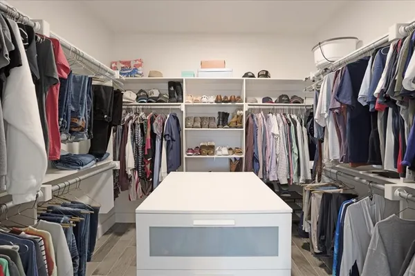 a view of walk in closet with clothes and shoes