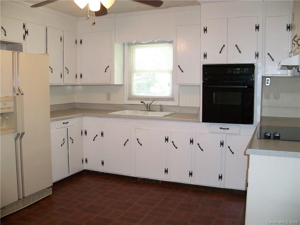 126 Pea Ridge Road Mill Spring, NC 28756 - Photo 8 of 24 a kitchen with granite countertop white cabinets white stainless steel appliances and sink