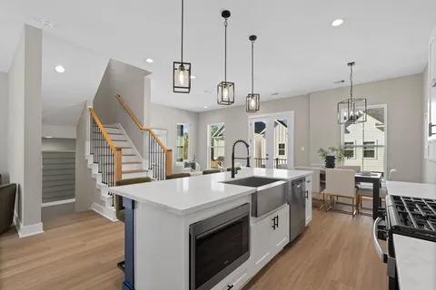 a kitchen with stainless steel appliances a stove a sink a center island and wooden floor
