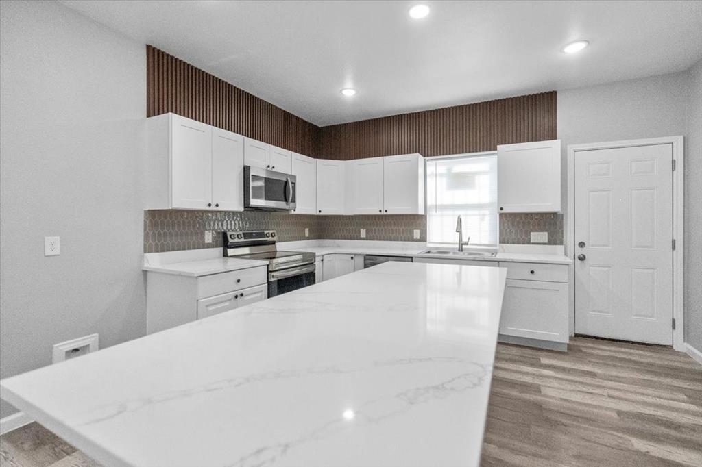 3512 Hamilton Avenue Dallas, TX 75210 - Photo 6 of 23 Kitchen with stainless steel appliances, light stone countertops, white cabinetry, light wood finished floors, and recessed lighting