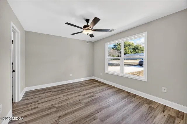 a view of an empty room with wooden floor and a window