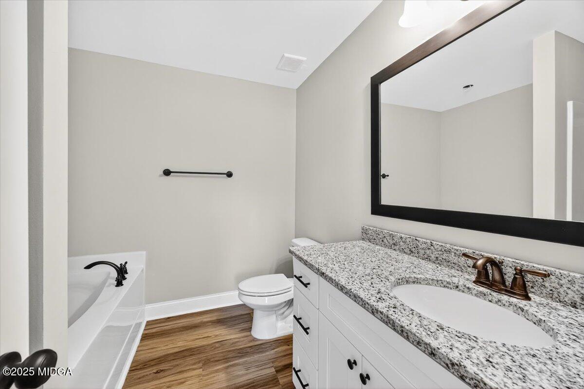 315 Lee Street Perry, GA 31069 - Photo 15 of 26 a bathroom with a granite countertop sink mirror vanity and toilet