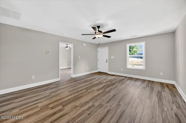 a view of an empty room with window and wooden floor