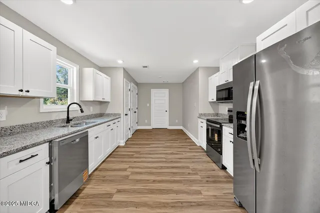 a large kitchen with stainless steel appliances granite countertop a refrigerator and a stove top oven