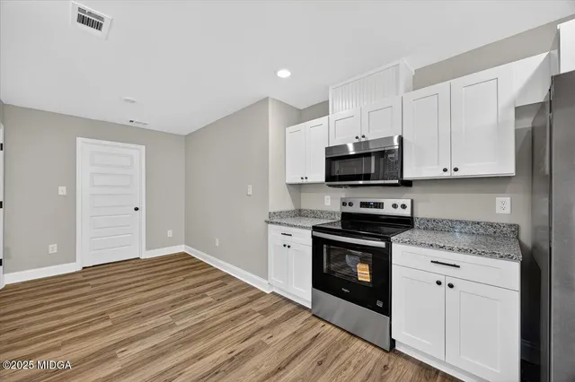 a kitchen with granite countertop white cabinets stainless steel appliances and a sink