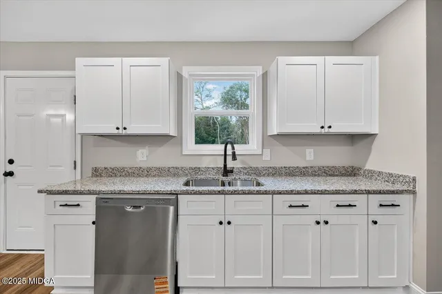 a kitchen with granite countertop white cabinets and a sink