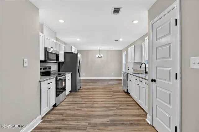 a large kitchen with stainless steel appliances a refrigerator and a stove top oven