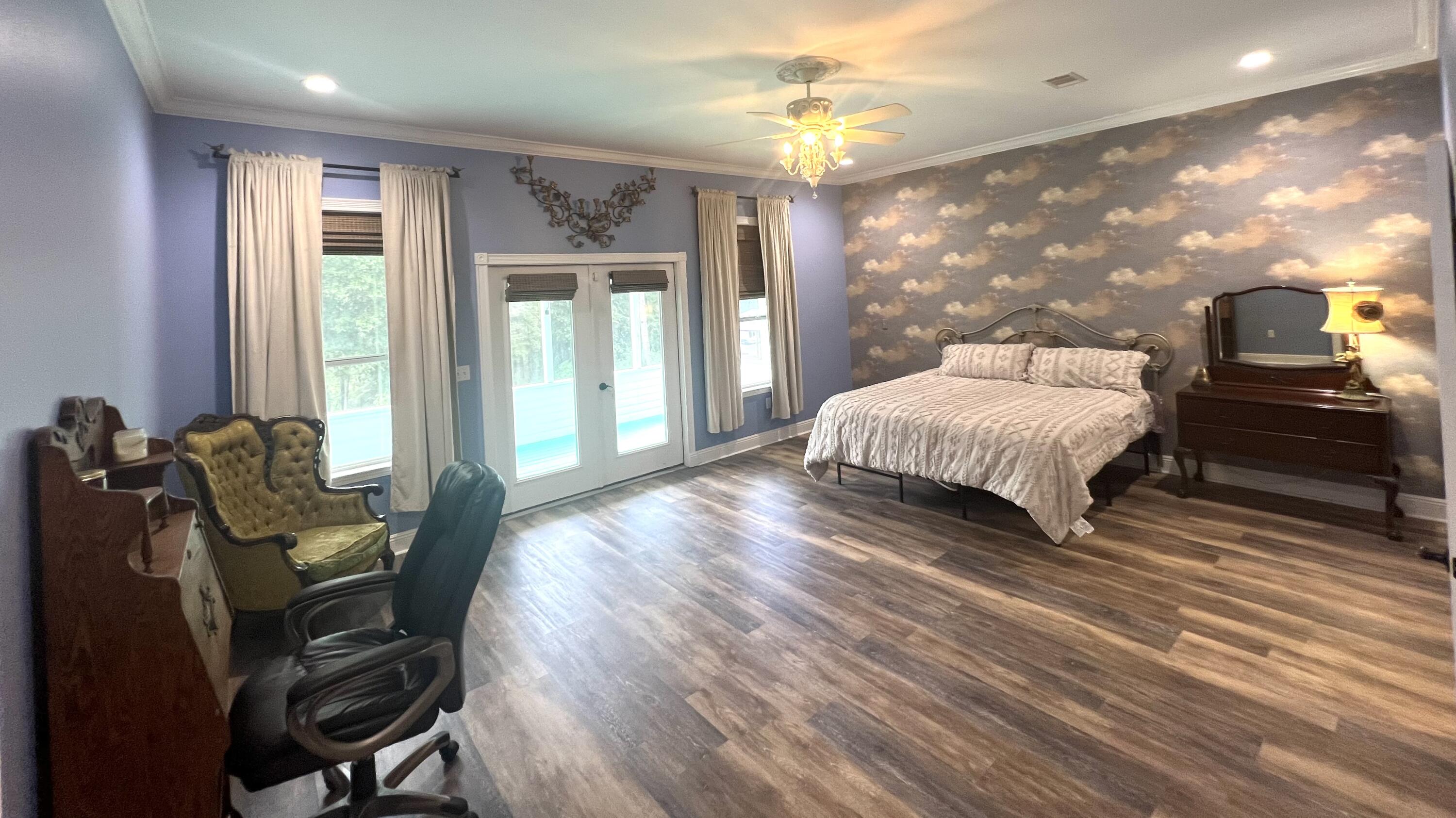 1111 Tallokas Road Crestview, FL 32536 - Photo 17 of 56 a spacious bedroom with a bed a dresser and wooden floor