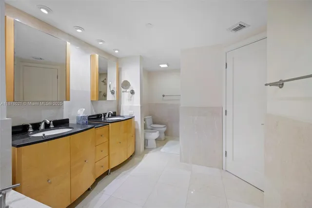 a large white kitchen with a sink a toilet and a refrigerator