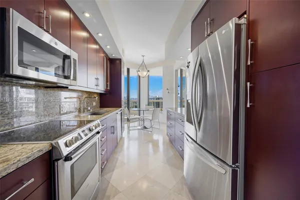 a kitchen with stainless steel appliances granite countertop a refrigerator a stove and a sink with wooden cabinets