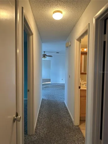 a view of a hallway with wooden floor and a bathroom