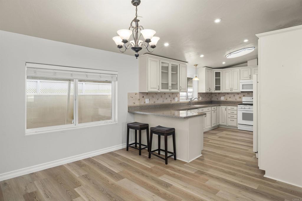 909 Richland Road, Unit 84 San Marcos, CA 92069 - Photo 17 of 35 a kitchen with stainless steel appliances granite countertop a stove top oven a sink dishwasher and white cabinets with wooden floor