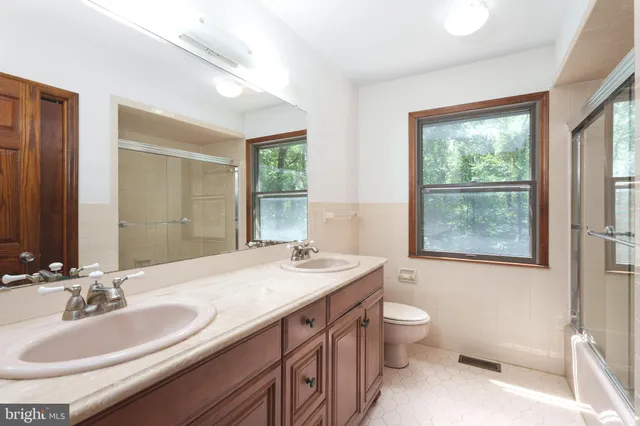 a bathroom with a sink a toilet a large mirror and a window