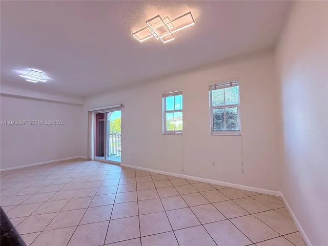 a view of an empty room with window and chandelier fan
