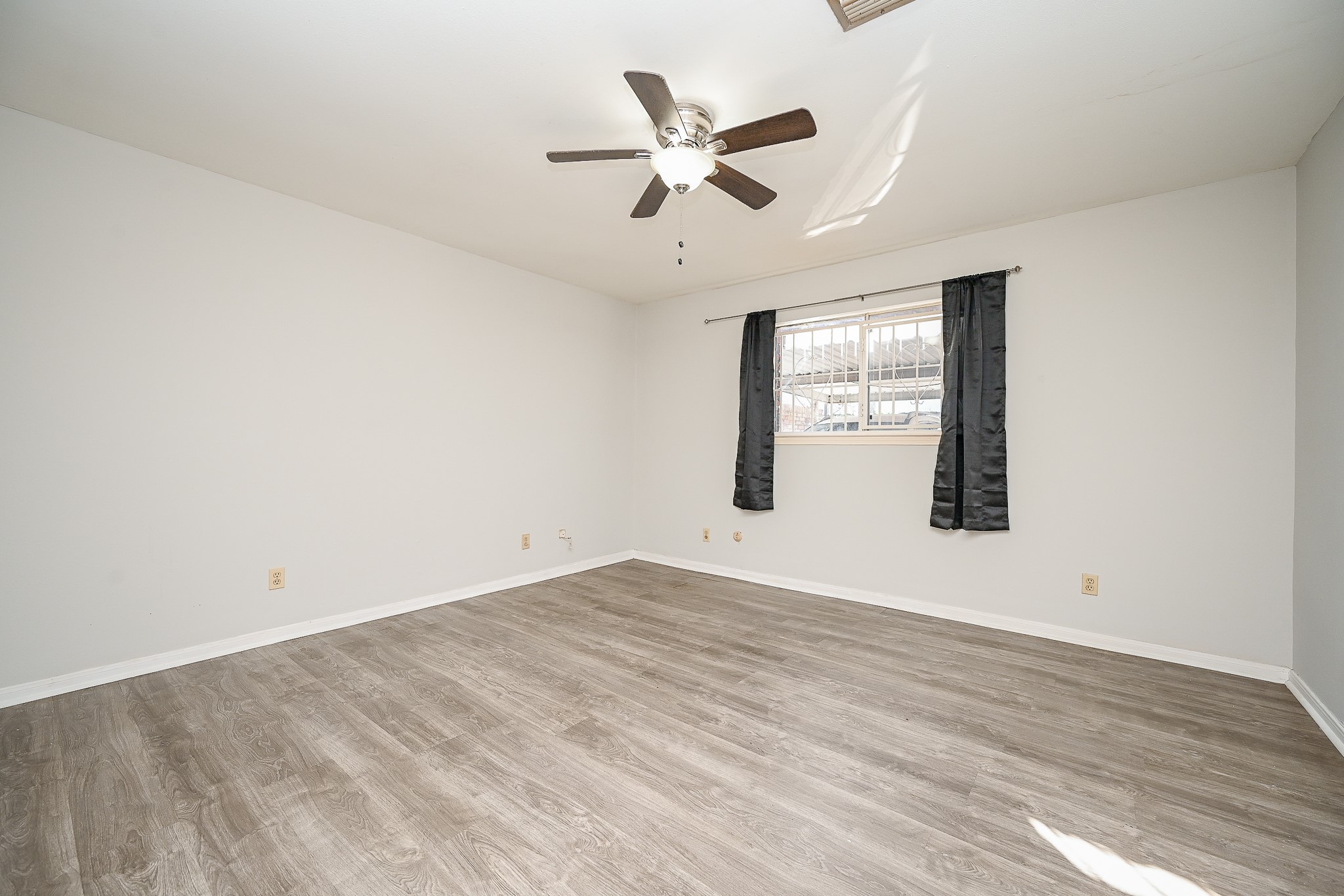 7878 Leonora Street Houston, TX 77061 - Photo 17 of 33 an empty room with wooden floor ceiling fan and windows