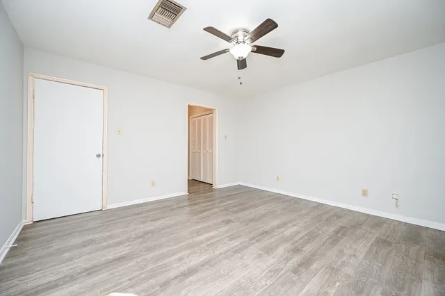 an empty room with wooden floor and ceiling fan