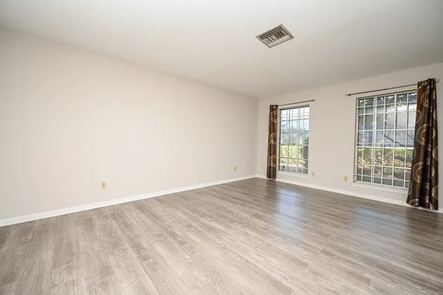 an empty room with wooden floor and windows