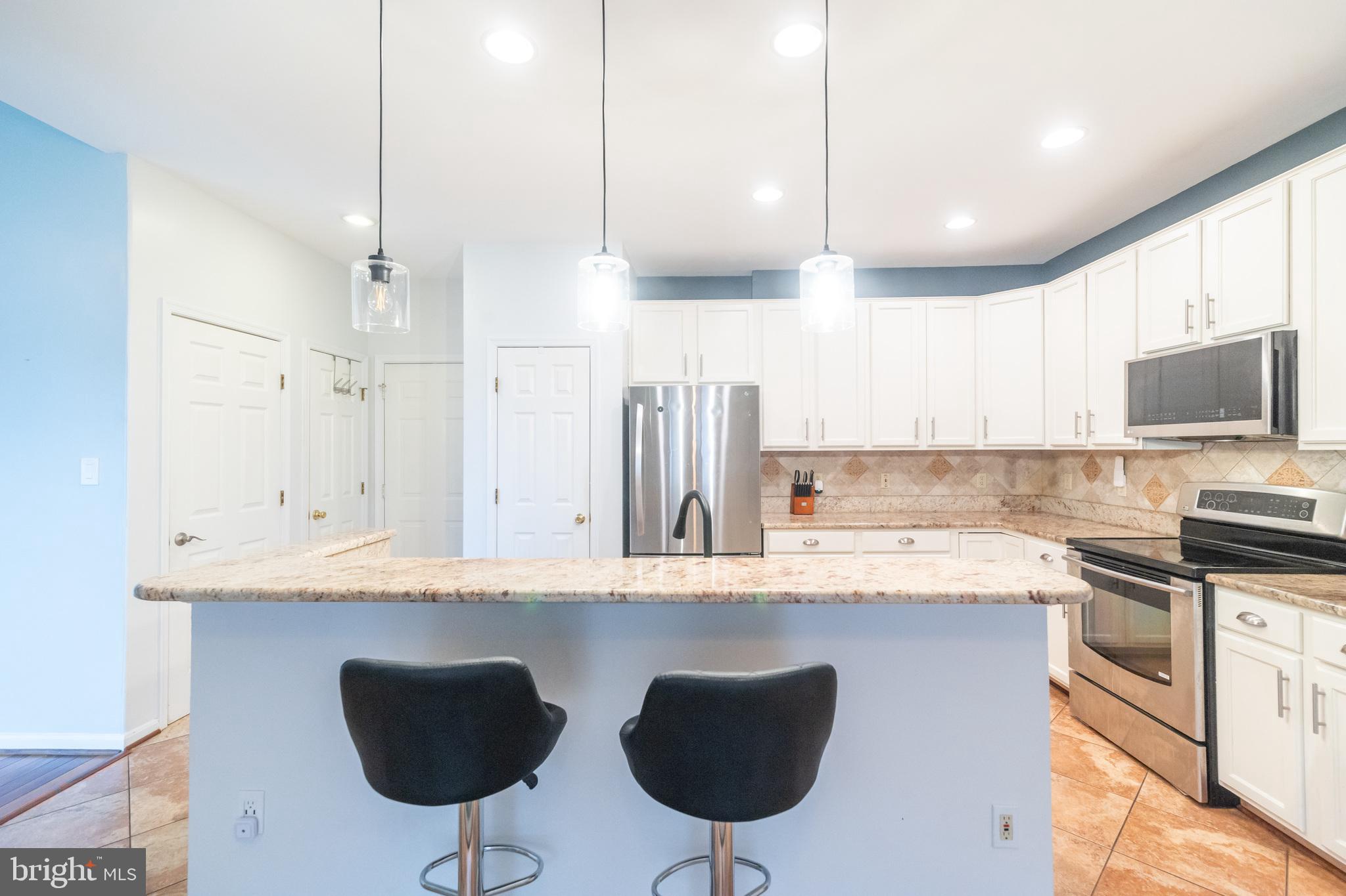 6005 Honnicut Drive Centreville, VA 20121 - Photo 4 of 29 a kitchen with stainless steel appliances granite countertop a sink a stove a refrigerator and island with wooden floor