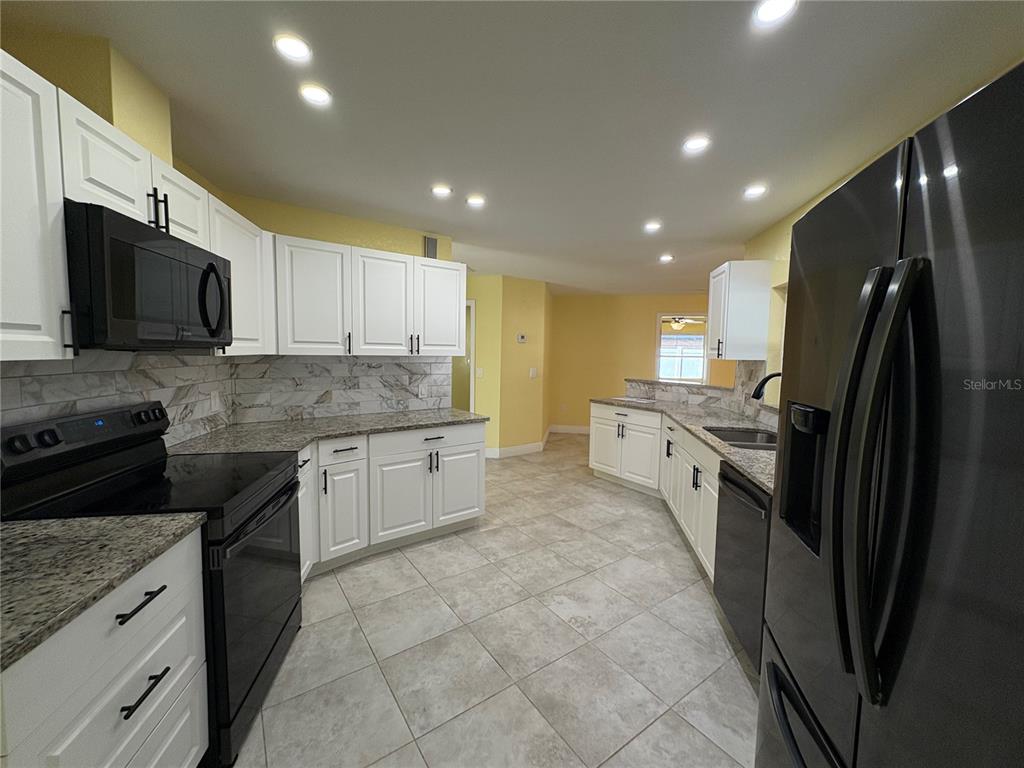1117 Angela Maria Road Sarasota, FL 34243 - Photo 11 of 52 a kitchen with granite countertop a refrigerator a sink a stove top oven and cabinets