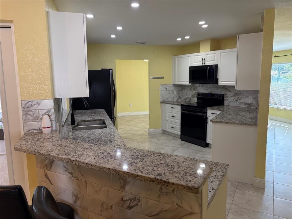 1117 Angela Maria Road Sarasota, FL 34243 - Photo 29 of 52 a kitchen with stainless steel appliances granite countertop a sink stove and refrigerator