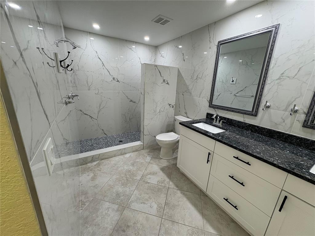 1117 Angela Maria Road Sarasota, FL 34243 - Photo 38 of 52 a spacious bathroom with a granite countertop sink a toilet and shower