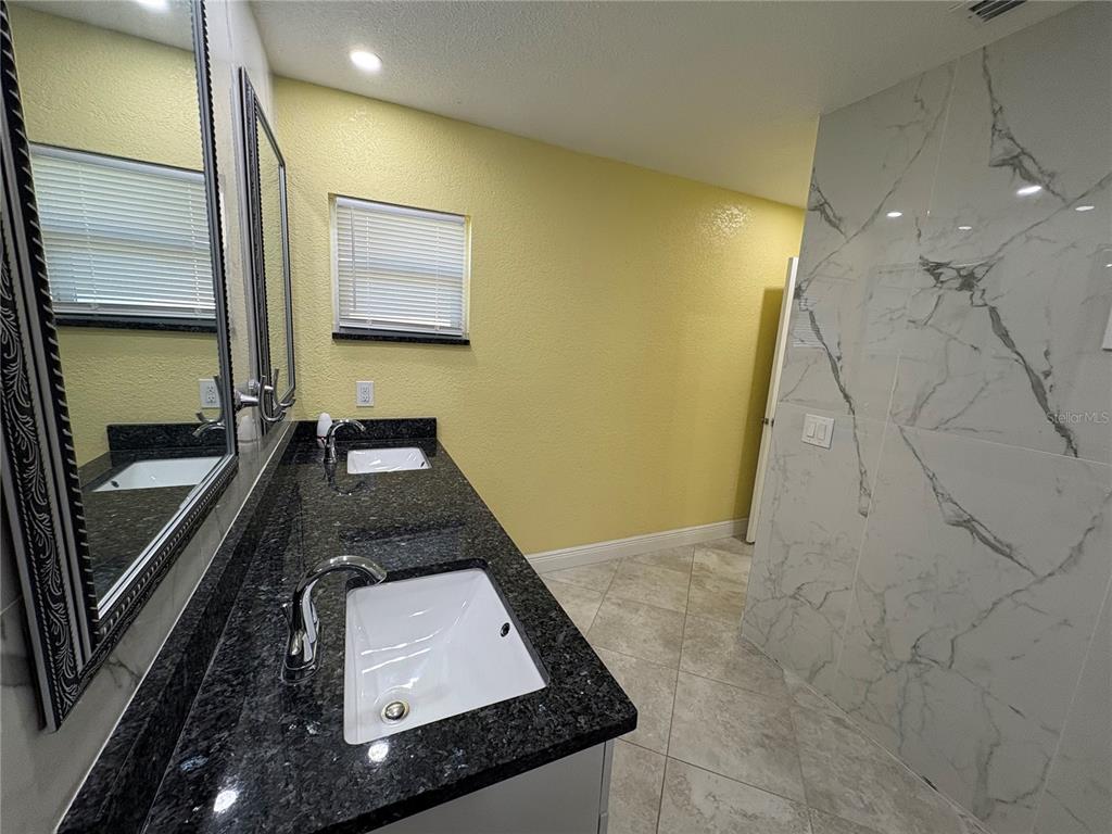 1117 Angela Maria Road Sarasota, FL 34243 - Photo 40 of 52 a bathroom with a granite countertop sink a toilet and a mirror